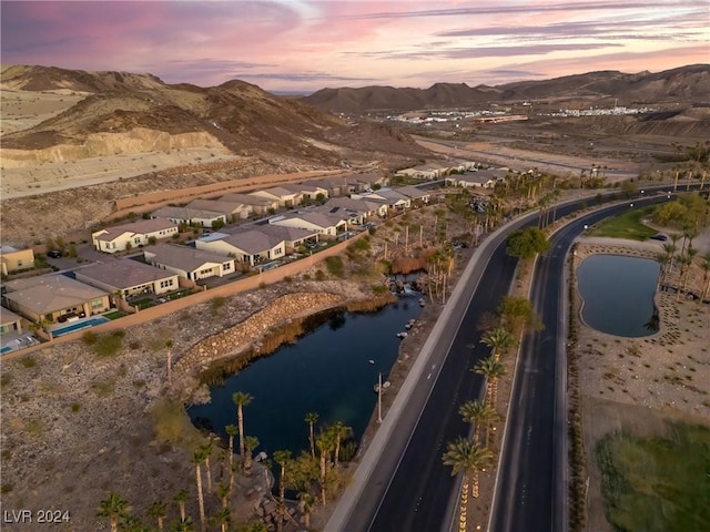 aerial view at dusk featuring a water and mountain view