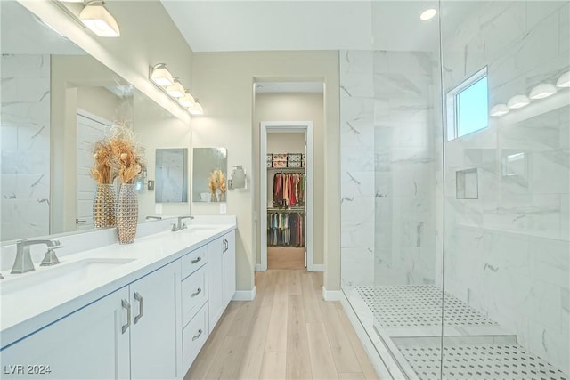 bathroom featuring wood-type flooring, tiled shower, and vanity