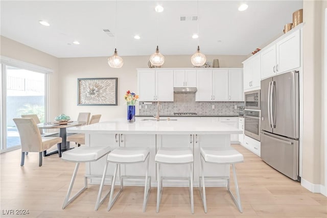 kitchen featuring sink, white cabinetry, appliances with stainless steel finishes, an island with sink, and pendant lighting