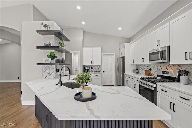 kitchen with white cabinetry, a center island with sink, stainless steel appliances, and vaulted ceiling