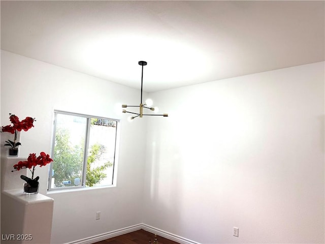 spare room featuring dark hardwood / wood-style flooring and an inviting chandelier