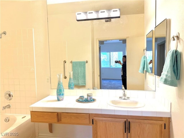 bathroom featuring vanity and tiled shower / bath