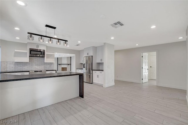 kitchen with backsplash, stainless steel appliances, white cabinetry, and hanging light fixtures