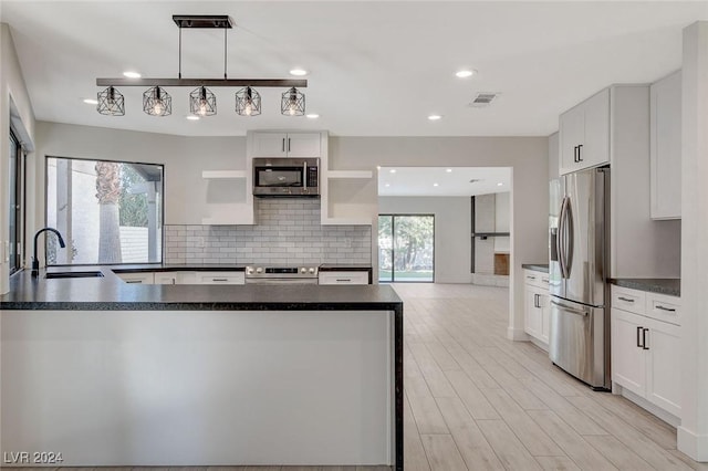 kitchen with sink, tasteful backsplash, decorative light fixtures, white cabinetry, and stainless steel appliances