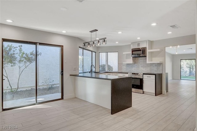 kitchen featuring pendant lighting, sink, kitchen peninsula, appliances with stainless steel finishes, and white cabinetry