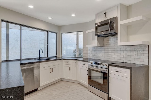 kitchen with stainless steel appliances, white cabinetry, tasteful backsplash, and sink