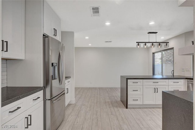 kitchen featuring stainless steel fridge, white cabinets, hanging light fixtures, and light wood-type flooring