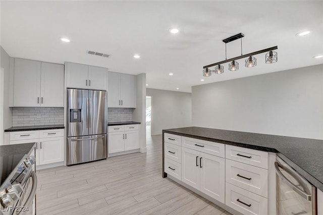 kitchen with white cabinets, decorative light fixtures, decorative backsplash, and stainless steel appliances