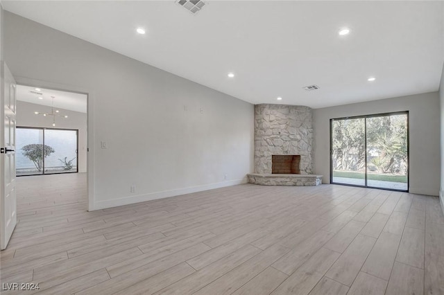 unfurnished living room featuring a fireplace, vaulted ceiling, and light wood-type flooring