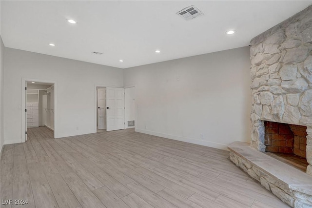 unfurnished living room with light hardwood / wood-style floors and a stone fireplace