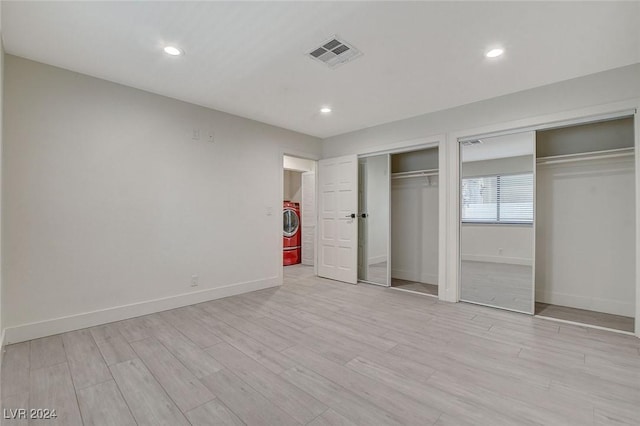 unfurnished bedroom with washer / clothes dryer, two closets, and light wood-type flooring