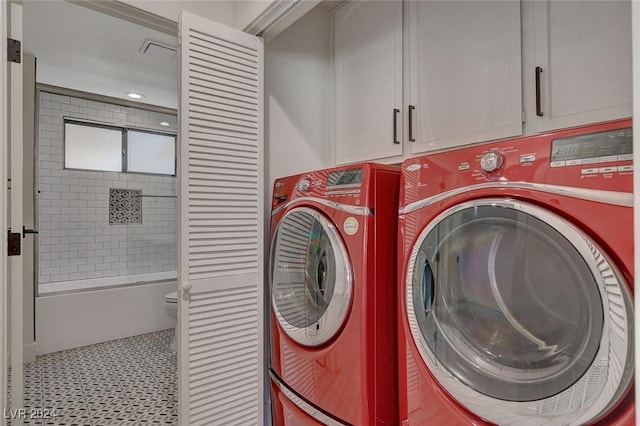 clothes washing area featuring washing machine and dryer and cabinets