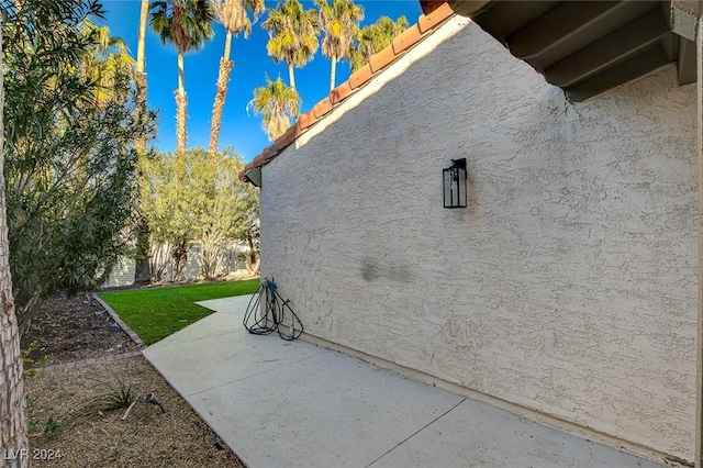 view of side of home with a lawn and a patio