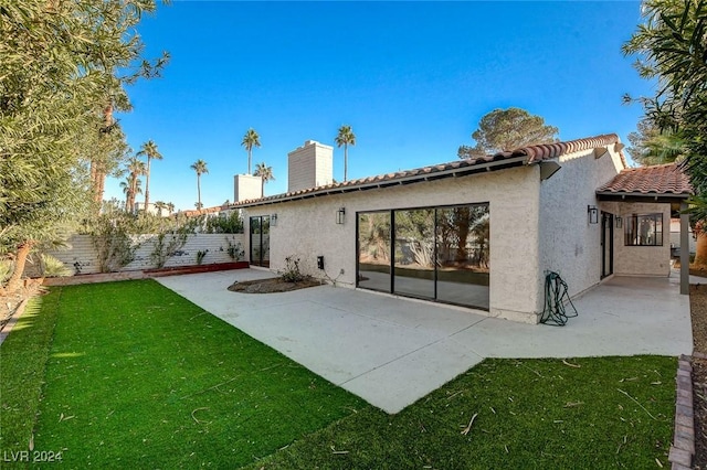 back of property with a lawn and a patio