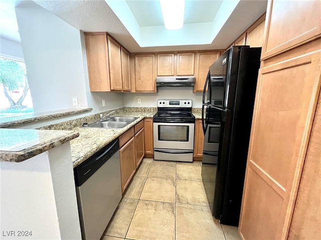 kitchen featuring light stone countertops, sink, a raised ceiling, kitchen peninsula, and appliances with stainless steel finishes