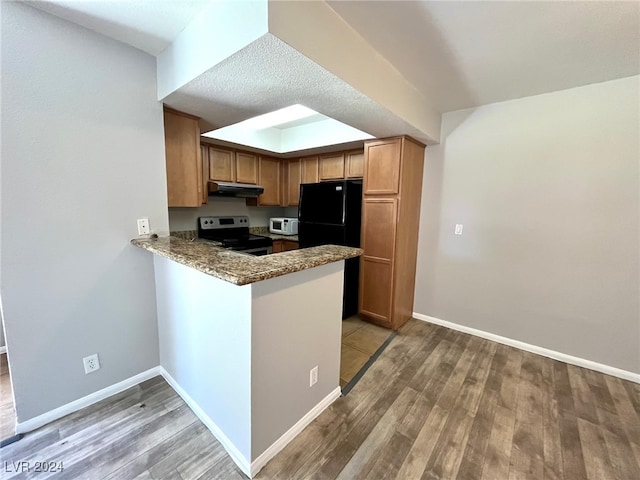 kitchen with kitchen peninsula, black refrigerator, light hardwood / wood-style flooring, and stainless steel range with electric cooktop