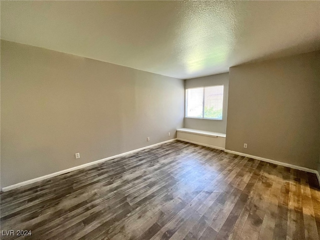 spare room featuring dark hardwood / wood-style floors and a textured ceiling