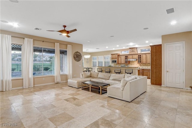 living room with ceiling fan with notable chandelier and a wealth of natural light