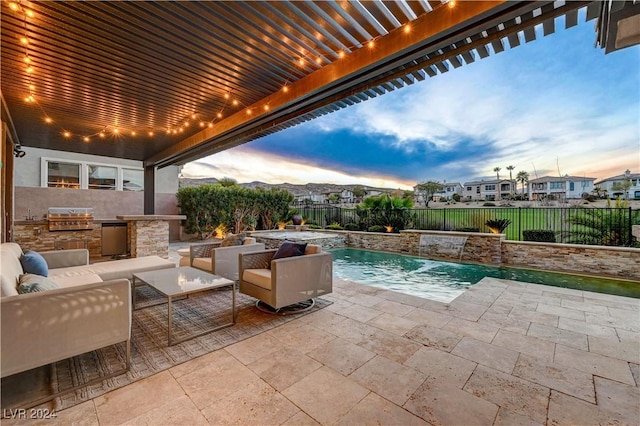 pool at dusk featuring an outdoor kitchen, an outdoor hangout area, pool water feature, area for grilling, and a patio