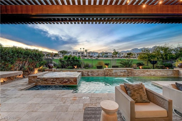 pool at dusk featuring a mountain view and pool water feature