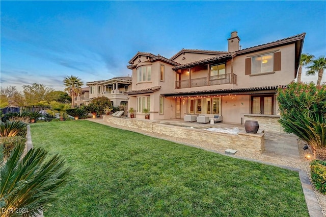 back of house featuring a lawn, a patio area, and a balcony