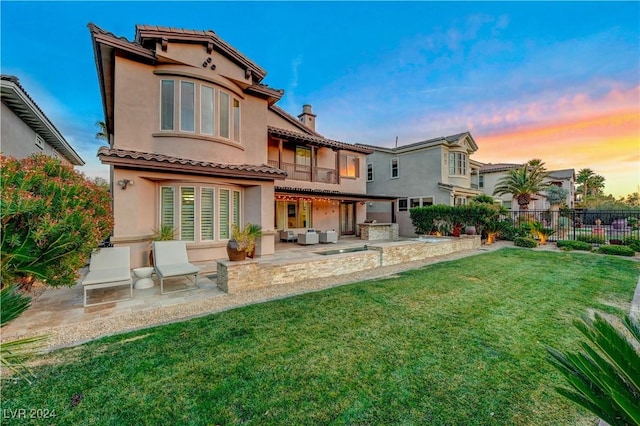 back house at dusk with a patio, a yard, and area for grilling