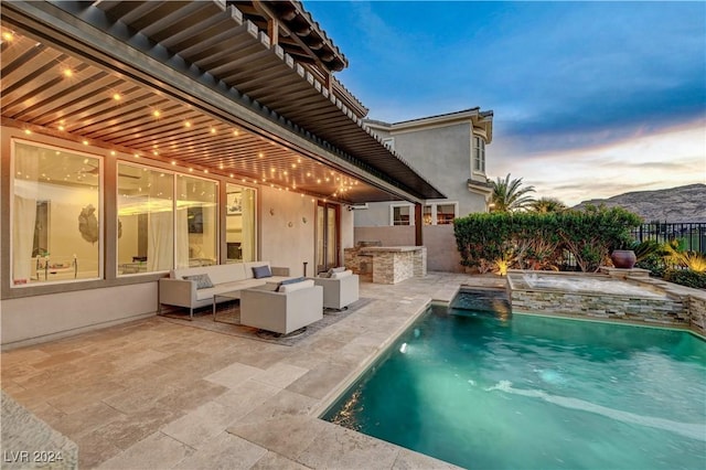 pool at dusk featuring an outdoor living space, pool water feature, exterior kitchen, and a patio