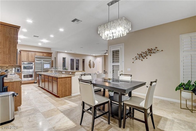 dining room with ceiling fan with notable chandelier and sink