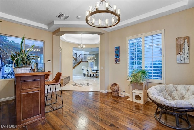 sitting room with a raised ceiling, dark wood-type flooring, and a notable chandelier