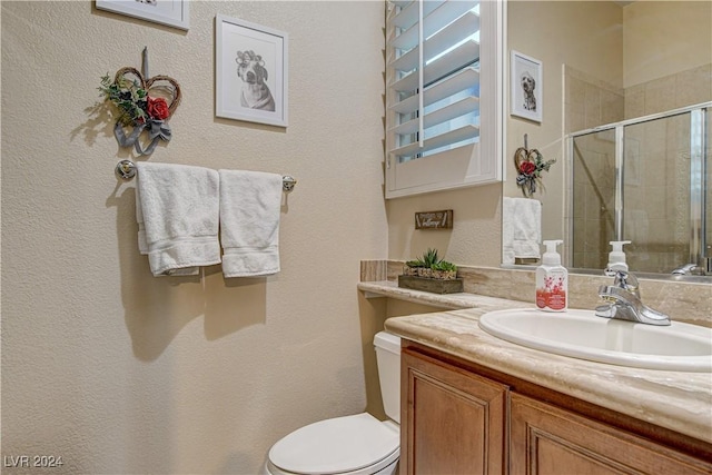 bathroom with vanity, toilet, and a shower with door