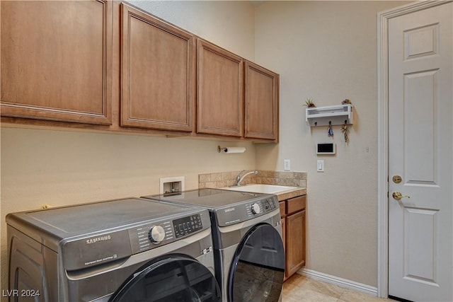 clothes washing area with washer and dryer, light tile patterned floors, cabinets, and sink