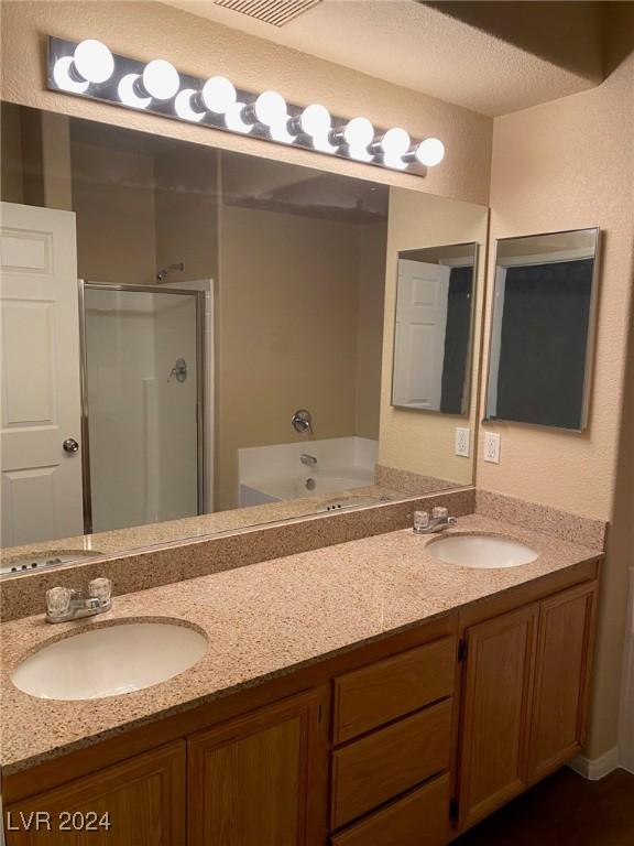 bathroom featuring vanity, a textured ceiling, and shower with separate bathtub