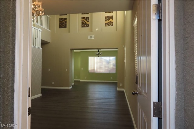 interior space featuring dark hardwood / wood-style flooring, a chandelier, and a high ceiling