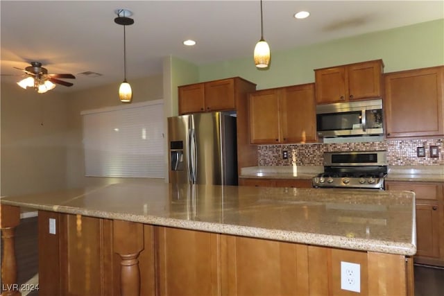 kitchen with hanging light fixtures, backsplash, and appliances with stainless steel finishes