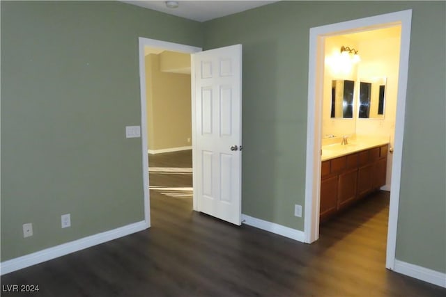 unfurnished bedroom featuring dark wood-type flooring, ensuite bath, and sink