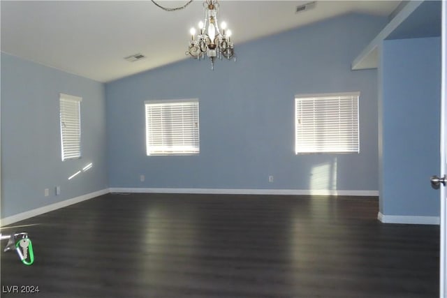 empty room featuring lofted ceiling, dark hardwood / wood-style floors, and a notable chandelier