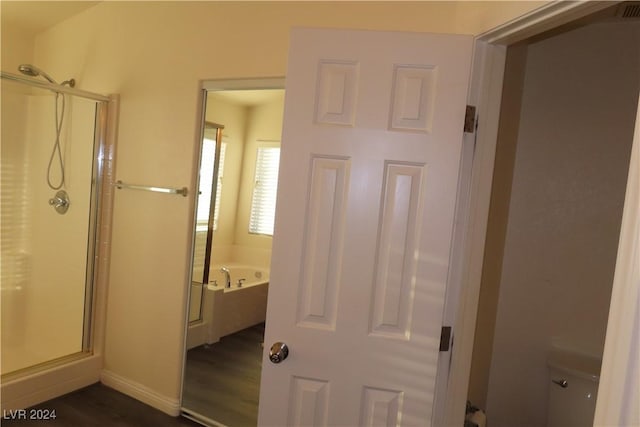 bathroom featuring hardwood / wood-style flooring, plus walk in shower, and toilet