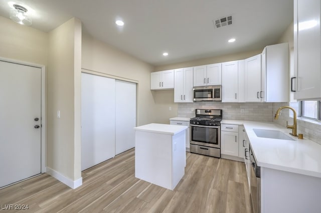 kitchen with stainless steel appliances, sink, a center island, light hardwood / wood-style floors, and white cabinetry