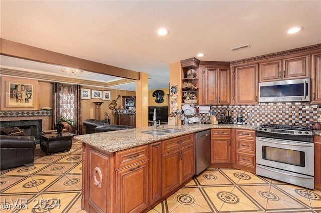 kitchen with sink, decorative backsplash, appliances with stainless steel finishes, light stone counters, and kitchen peninsula