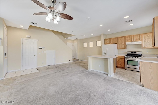 kitchen with a center island, light carpet, stainless steel gas range, ceiling fan, and white fridge with ice dispenser