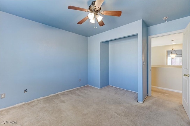 unfurnished bedroom featuring ceiling fan, a closet, and light carpet