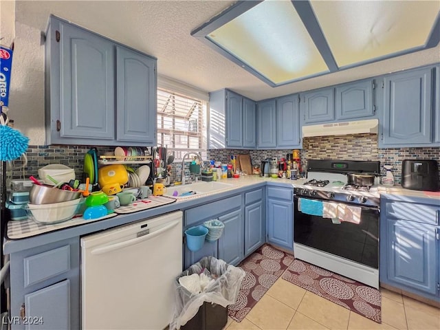 kitchen with light tile patterned flooring, white appliances, sink, and blue cabinets