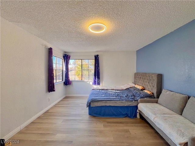 bedroom with a textured ceiling and light hardwood / wood-style floors