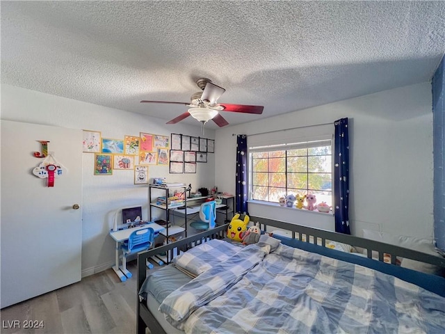 bedroom with ceiling fan, hardwood / wood-style floors, and a textured ceiling