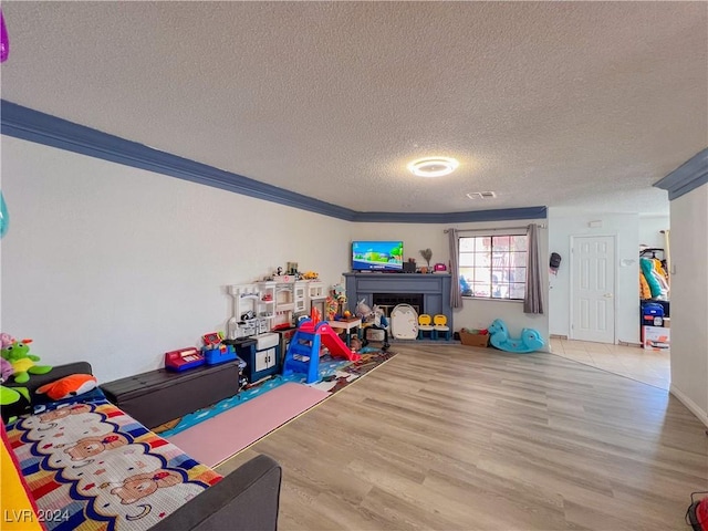 rec room featuring hardwood / wood-style flooring, ornamental molding, and a textured ceiling