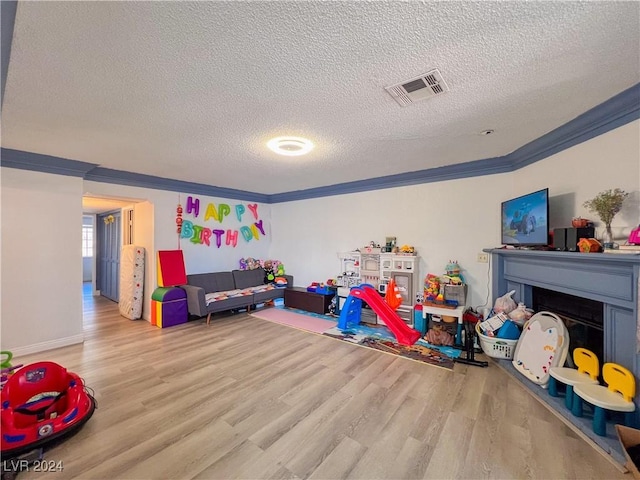 recreation room with crown molding, light hardwood / wood-style flooring, and a textured ceiling