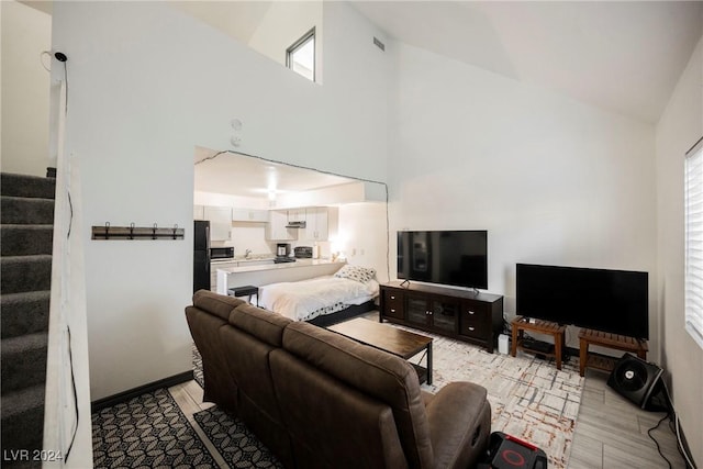 living room with light hardwood / wood-style floors, high vaulted ceiling, and plenty of natural light