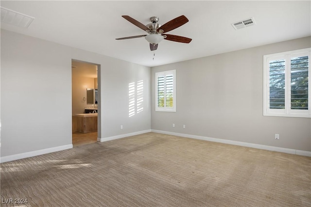 empty room featuring ceiling fan and light colored carpet