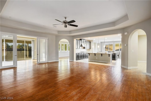 unfurnished living room featuring french doors, light wood-type flooring, plenty of natural light, and ceiling fan