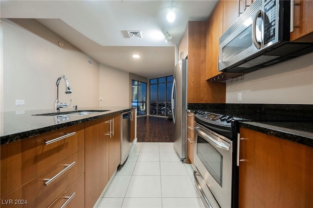 200 W Sahara Ave Unit 1510, Las Vegas, NV 89102 - kitchen with stainless steel appliances, brown cabinetry, dark stone countertops, light tile patterned floors, and modern cabinets